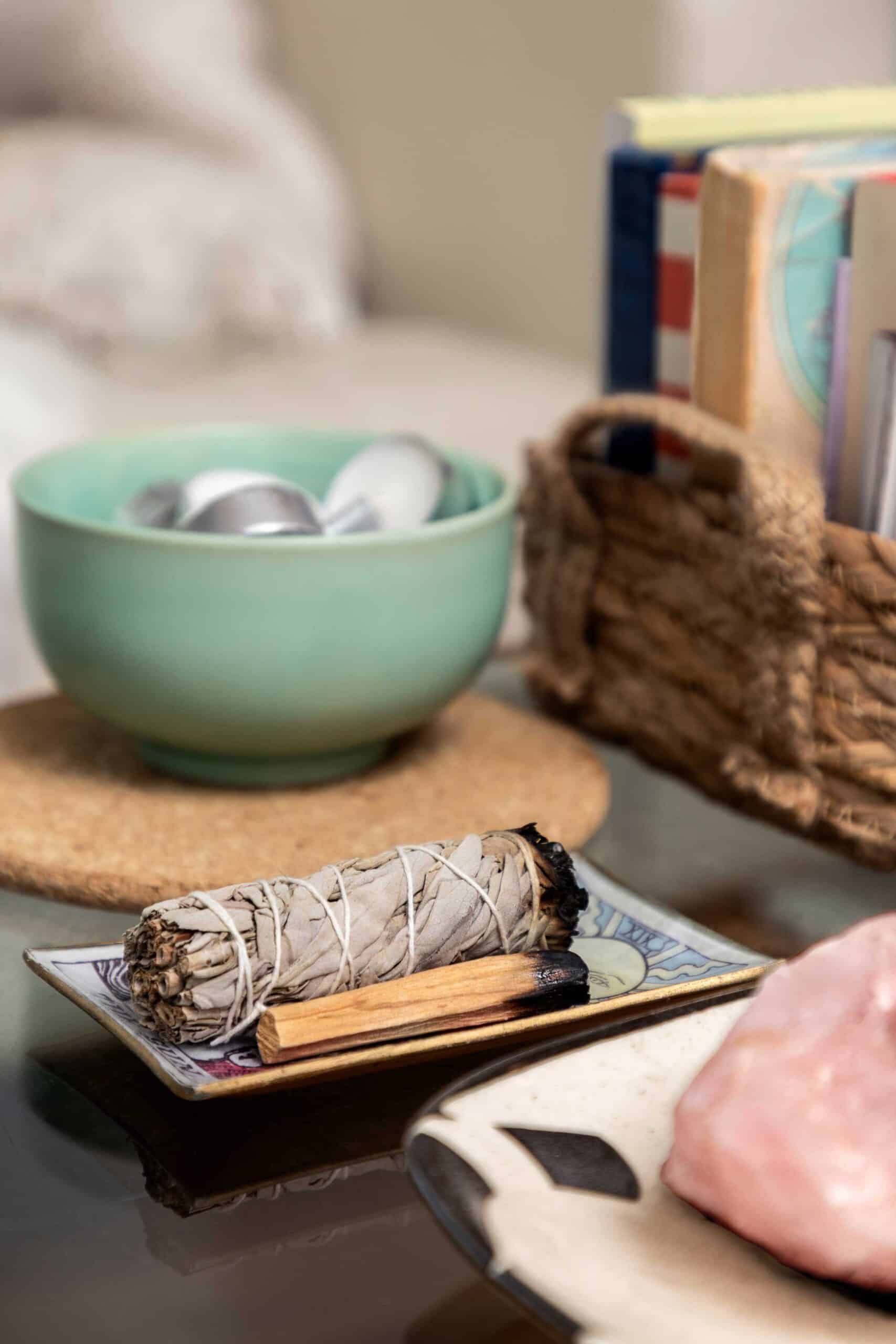 A bundle of sage smudge sticks with cinnamon sticks on a decorative tray.